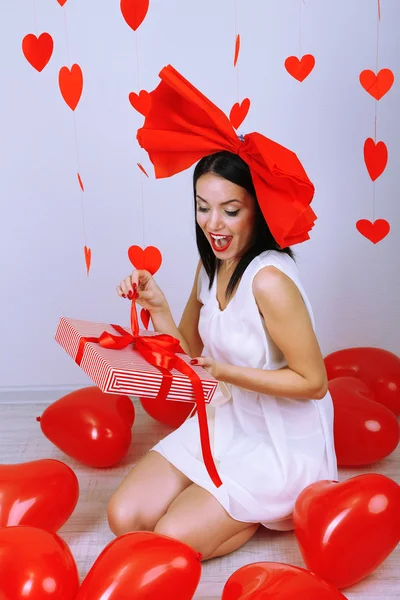 Attraente giovane donna con regalo e palloncini in camera a San Valentino — Foto Stock