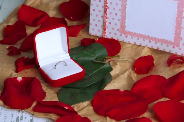 Anneau entouré de roses et pétales sur table en bois close-up — Photo