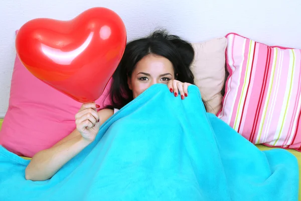 Beautiful woman with balloon in bed on Valentine Day — Stock Photo, Image