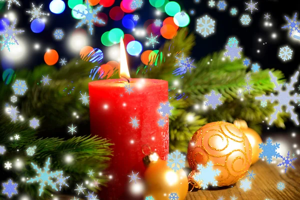 Composición con vela ardiente, abeto y decoraciones navideñas sobre fondo de luces multicolor —  Fotos de Stock