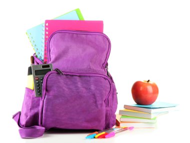 Okul malzemelerinin bulunduğu mor sırt çantası beyazın üzerinde.