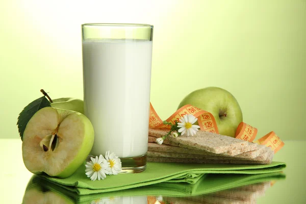 Copo de kefir, maçãs, batatas fritas e fita métrica, sobre fundo verde — Fotografia de Stock