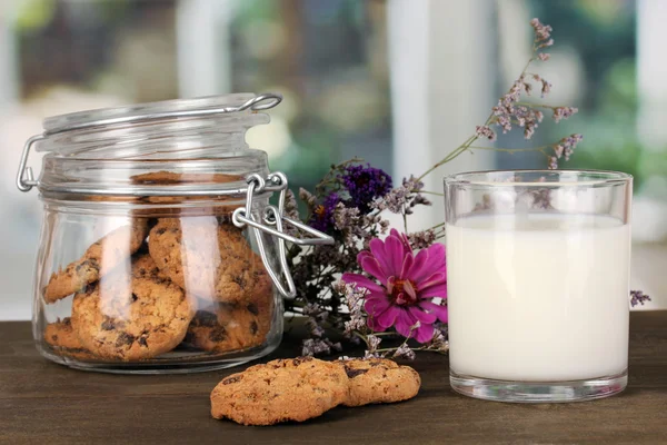 Sklenici mléka s cookies na dřevěný stůl na detail pozadí windows — Stock fotografie