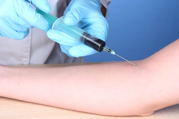 Nurse takes blood from the veins on blue background — Stock Photo, Image