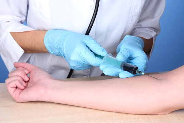 Enfermeira tira sangue das veias em fundo azul — Fotografia de Stock