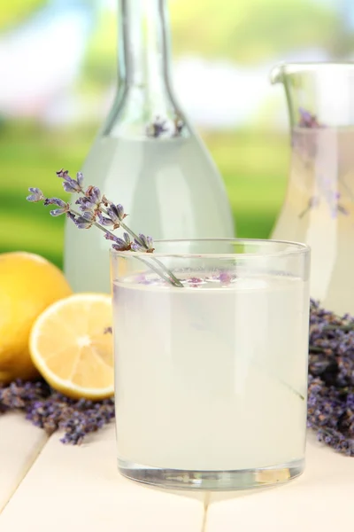 Lavender lemonade in bottle and jug, on bright background — Stock Photo, Image