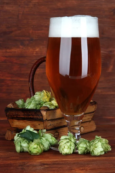 Verre de bière et houblon, sur table en bois — Photo