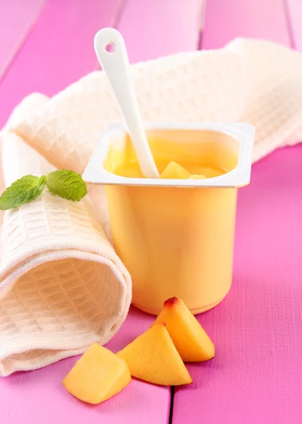 Chutné jogurt s kousky čerstvého ovoce, na barevné dřevěné pozadí — Stock fotografie
