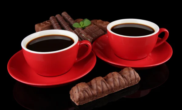 Copos vermelhos de café forte e barras de chocolate isoladas em preto — Fotografia de Stock