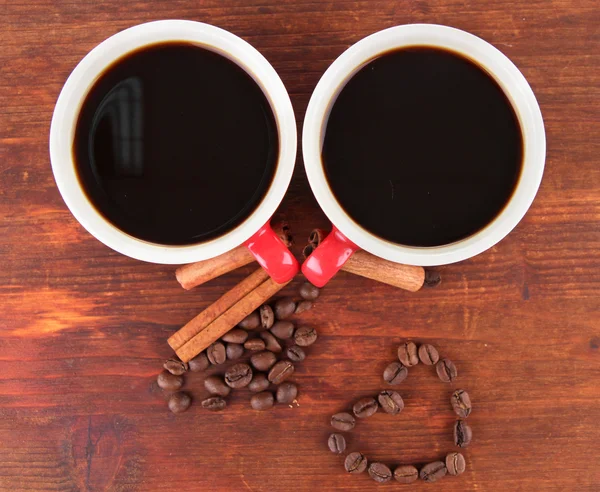 Tazas rojas de café fuerte y granos de café sobre fondo de madera —  Fotos de Stock