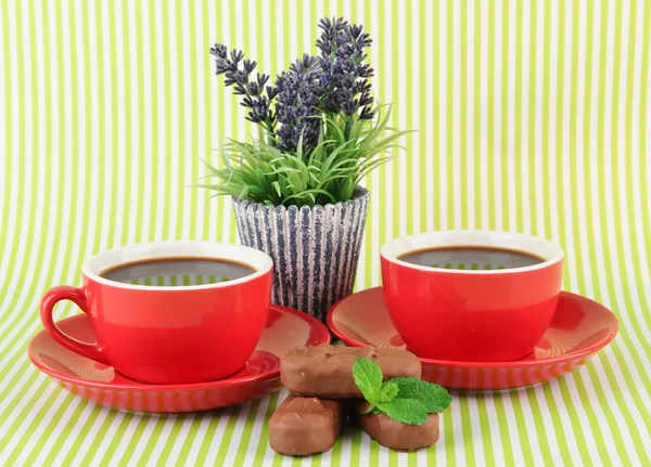 Rote Tassen mit starkem Kaffee und Schokoriegeln auf gestreiftem Hintergrund — Stockfoto