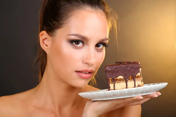 Портрет красивой молодой девушки с шоколадным кексом на коричневом фоне — стоковое фото