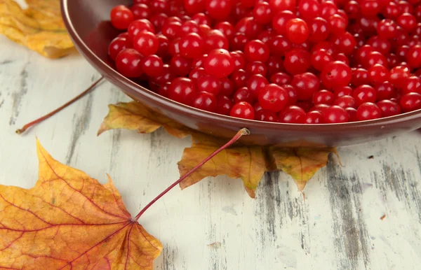 红色浆果的荚蒾在碗和木背景萎黄的树叶 — 图库照片
