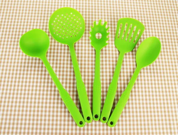 Plastic kitchen utensils on fabric background — Stock Photo, Image