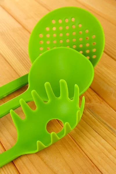 Plastic kitchen utensils on wooden background — Stock Photo, Image