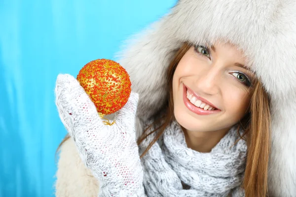 Bella ragazza sorridente con palla di Natale su sfondo blu — Foto Stock