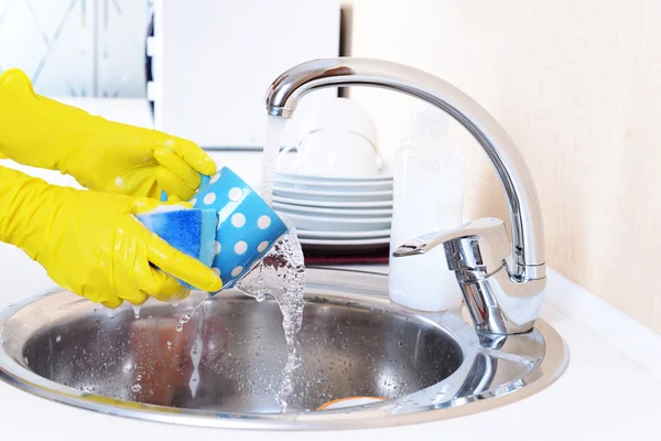 Fermer les mains de la femme qui lave la vaisselle dans la cuisine — Photo