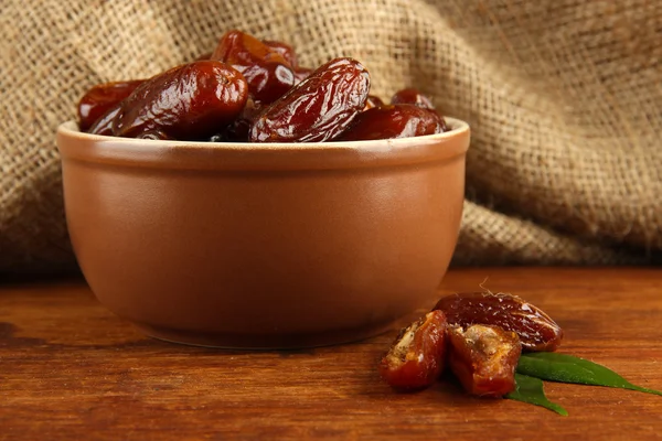 Dates séchées dans un bol sur la table sur fond de sac — Photo