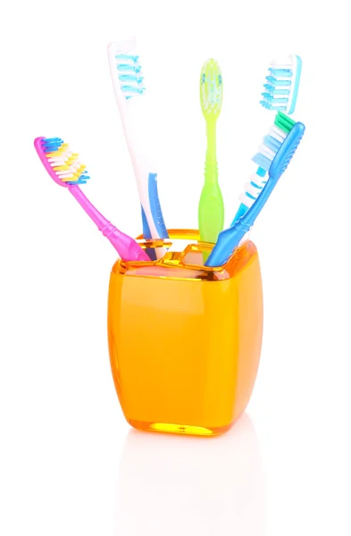 Escovas de dentes em vidro laranja isolado em branco — Fotografia de Stock
