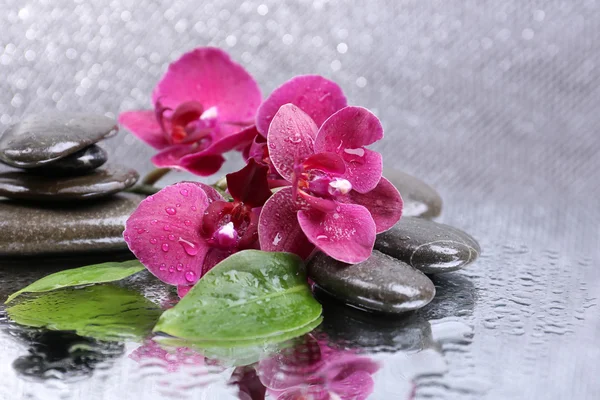 Composición con hermosa orquídea floreciente con gotas de agua y piedras de spa, sobre fondo de color claro — Foto de Stock