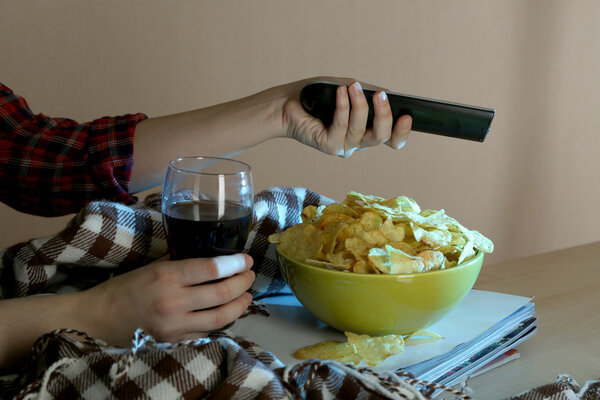 Someone watching TV with crisps and cola in room