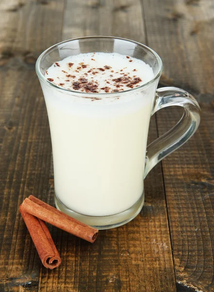 Cup of eggnog with cinnamon on wooden background — Stock Photo, Image