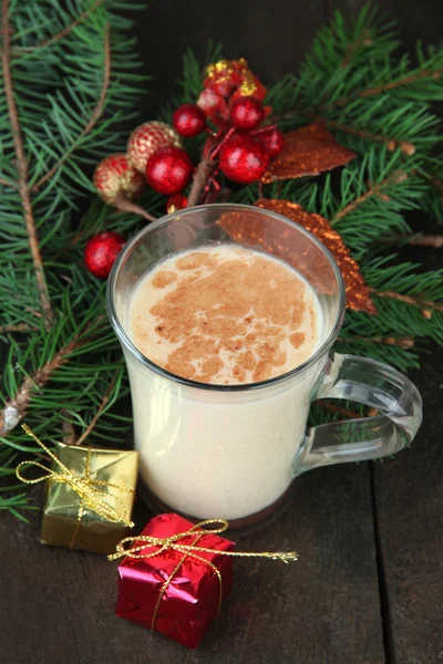 Tazza di zabaione con rami di abete e decorazioni natalizie su sfondo di legno — Foto Stock