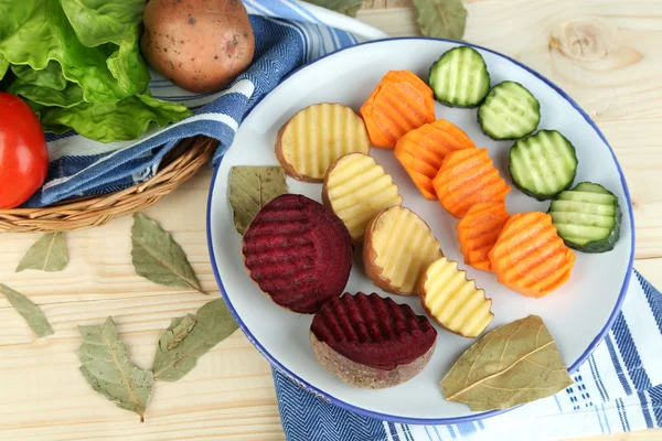 Beautiful sliced vegetables, on plate, on wooden background — Stock Photo, Image
