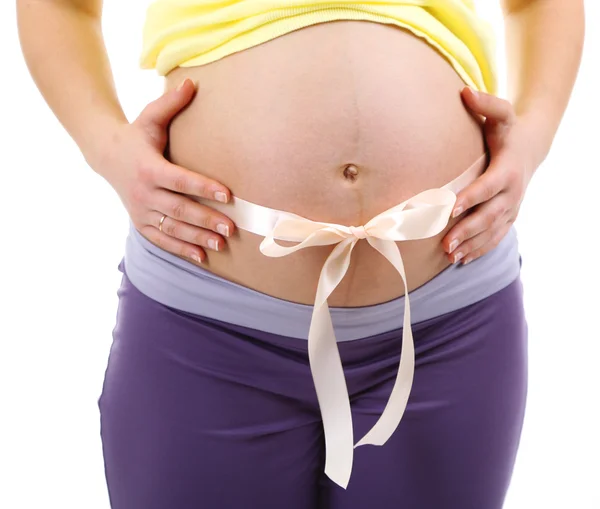 Pregnant young woman with beige bow on belly isolated on white — Stock Photo, Image