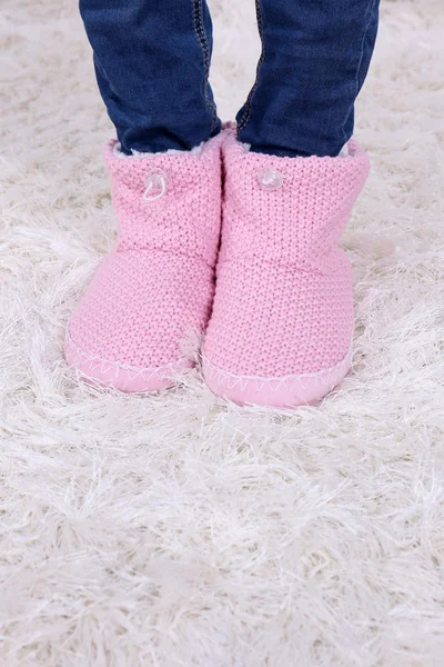 Female legs in blue jeans trousers and home winter shoes, on white carpet background — Stock Photo, Image