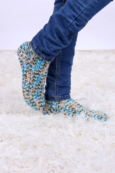 Female legs in blue jeans trousers and colorful socks on white carpet background — Stock Photo, Image