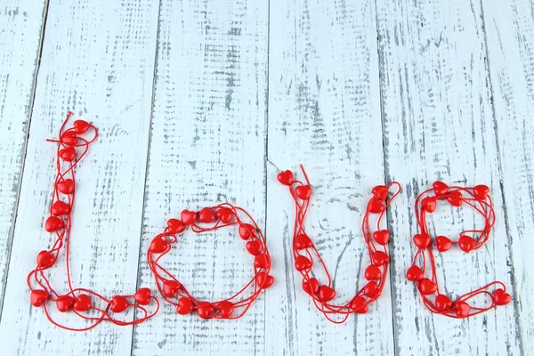 Heart-shaped beads on string on wooden background — Stock Photo, Image