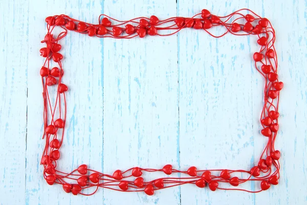 Heart-shaped beads on string on wooden background — Stock Photo, Image