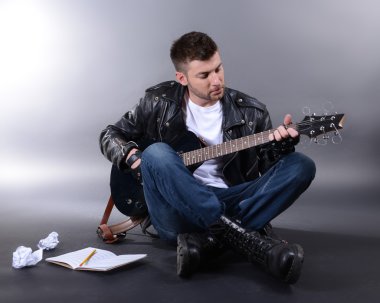 genç müzisyen gri arka plan üzerinde gitar çalmak