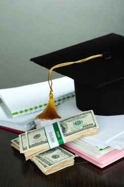 Mezuniyet veya gri arka plan üzerinde ahşap masa üzerinde eğitim için para