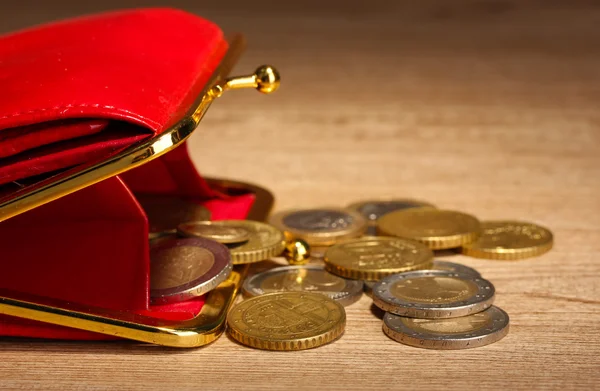 Billetera roja femenina con monedas sobre fondo de madera — Foto de Stock