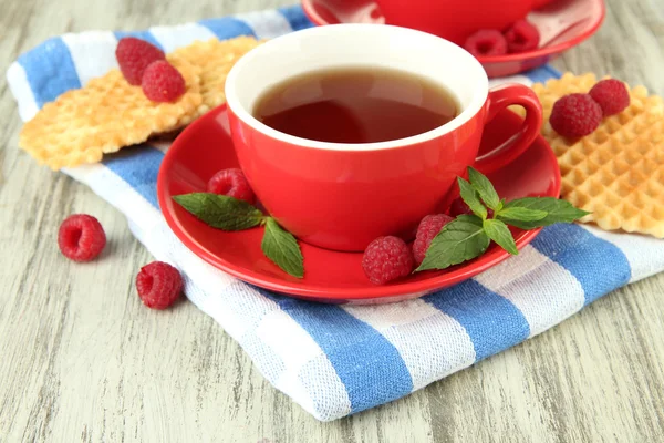 Tazas de té con galletas y frambuesas en primer plano de la mesa — Foto de Stock