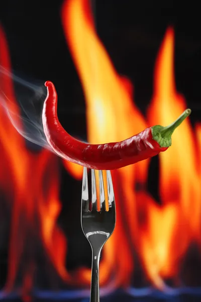 Red hot chili pepper on fork, on fire background — Stock Photo, Image