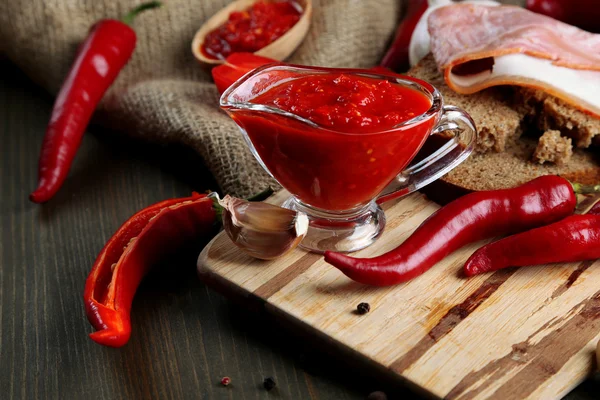 Composizione con salsa su pane, peperoncino rosso e aglio, su sacco, su fondo di legno — Foto Stock