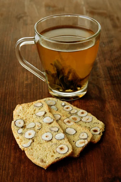 Průhledný šálek zeleného čaje s cookies na dřevěné pozadí — Stock fotografie