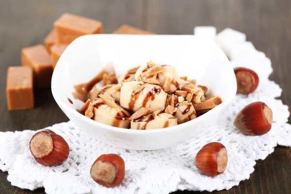 Many toffee in bowl on napkin on wooden table — Stock Photo, Image