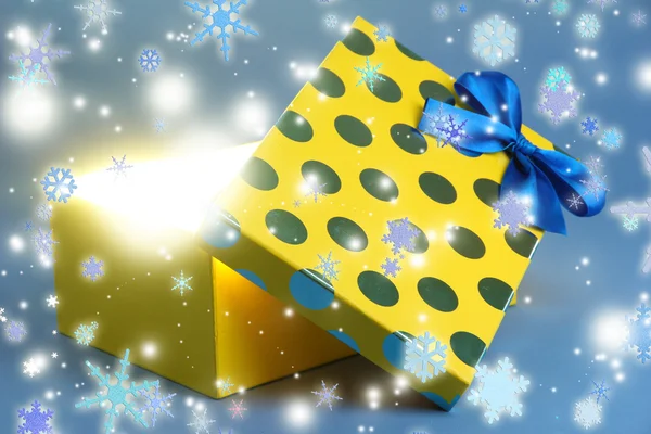 Gift box with bright light on it on blue background — Stock Photo, Image