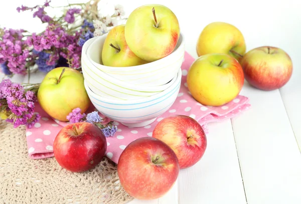 Saftige Äpfel auf Teller auf weißem Holztisch — Stockfoto