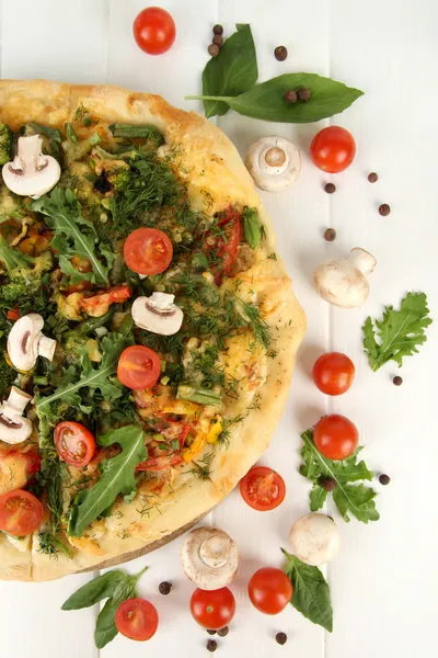 Вкусная вегетарианская пицца и овощи на деревянном столе — стоковое фото