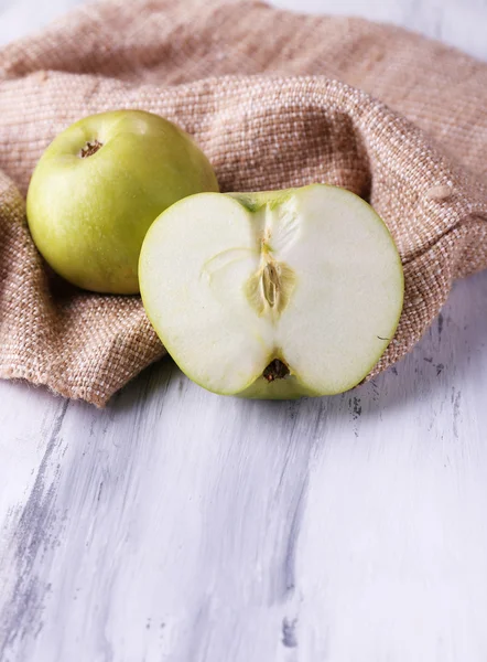 Яблоки и мешковина на деревянном фоне — стоковое фото