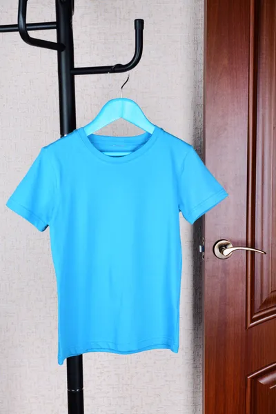 T-shirt hanging on hanger near door — Stock Photo, Image