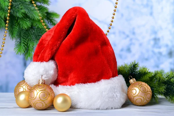 Komposition mit Weihnachtsmann rotem Hut und Weihnachtsdekoration auf hellem Hintergrund — Stockfoto