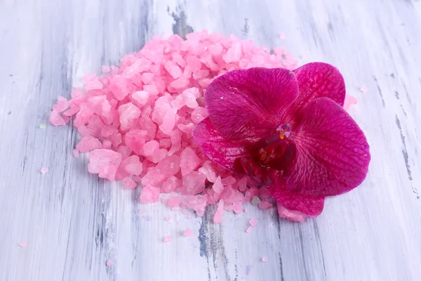 Schöne blühende Orchideenblume und Haufen Meersalz, auf farbigem Holzhintergrund — Stockfoto