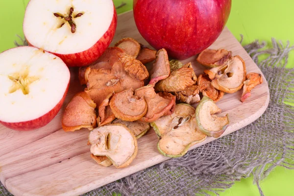 Pommes séchées, sur planche à découper, sur fond de bois couleur — Photo