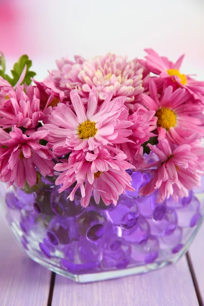 Lindas flores em vaso com hidrogel na mesa sobre fundo brilhante — Fotografia de Stock